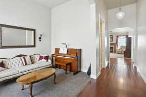 Living room with dark wood-type flooring, arched walkways, and a warm lit fireplace