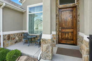 Doorway to property featuring stone siding and stucco siding