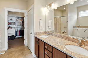 Full bath with double vanity, a spacious closet, and light tile patterned flooring