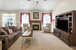 Living room featuring carpet floors, recessed lighting, a tiled fireplace, vaulted ceiling, and a ceiling fan