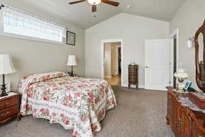Bedroom featuring carpet floors, vaulted ceiling, and a ceiling fan