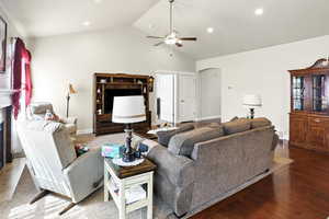 Living area featuring a glass covered fireplace, high vaulted ceiling, ceiling fan, recessed lighting, and wood finished floors