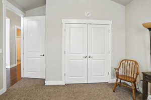 Sitting room with dark colored carpet and lofted ceiling