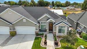 View of front of home with roof with shingles, driveway, stone siding, stucco siding, and an attached garage