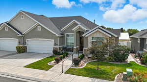 Craftsman-style house with roof with shingles, concrete driveway, a front yard, stone siding, and stucco siding