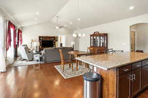 Kitchen with light stone countertops, pendant lighting, arched walkways, open floor plan, and a center island