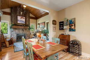 Dining area featuring light wood finished floors, wood ceiling, a fireplace, and lofted ceiling