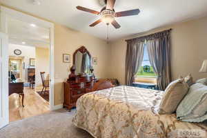 Bedroom featuring light carpet, a ceiling fan, and light wood-style floors