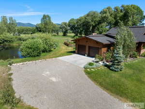 View of front of property with concrete driveway, a garage, a water and mountain view, a front yard, and a shingled roof