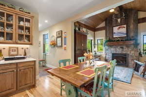 Dining area featuring light wood-style flooring, a fireplace, lofted ceiling, wood ceiling, and recessed lighting