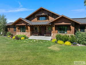 View of front facade featuring a porch, stone siding, and a front yard