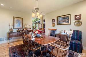 Dining area with light wood-style flooring and a chandelier
