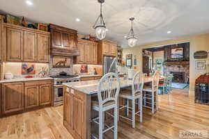 Kitchen with brown cabinets, an island with sink, light stone countertops, a kitchen breakfast bar, and tasteful backsplash