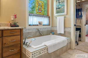 Bathroom with a garden tub, light tile patterned floors, and vanity