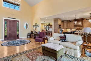 Living area with a chandelier, wood finished floors, a towering ceiling, and recessed lighting