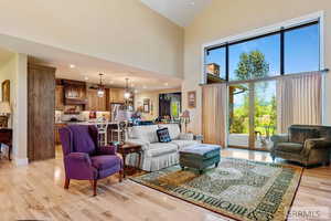 Living room featuring high vaulted ceiling, light wood-type flooring, recessed lighting, and a chandelier