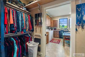 Walk in closet with independent washer and dryer and light tile patterned floors