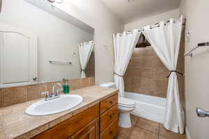 Full bathroom featuring shower / bath combo with shower curtain, light tile patterned floors, and vanity