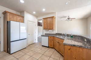 Kitchen with brown cabinets, white appliances, a textured ceiling, a ceiling fan, and recessed lighting