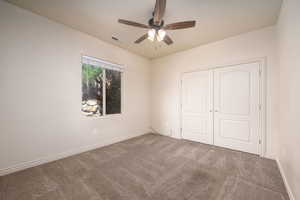 Unfurnished bedroom featuring carpet floors, a closet, and a ceiling fan