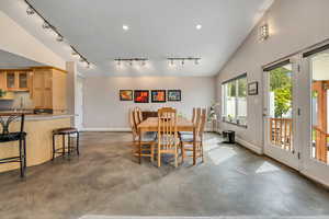 Dining area with custom concrete floors, vaulted ceilings, and natural light