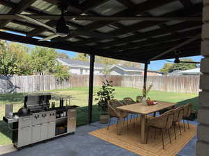 Fenced backyard with outdoor dining space, a patio, ceiling fan, and grilling area