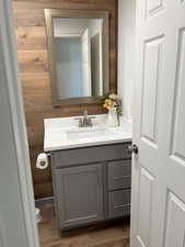 Bathroom featuring vanity, wood walls, and light wood-style floors
