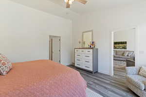 Bedroom with dark wood-style floors, ceiling fan, and high vaulted ceiling