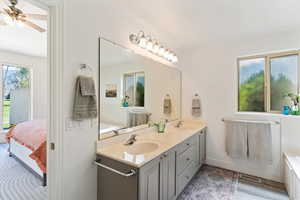 Bathroom with a bath, double vanity, ensuite bath, and light wood-style floors