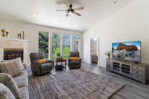 Living room featuring dark wood-style floors, a tile fireplace, a ceiling fan, recessed lighting, and high vaulted ceiling