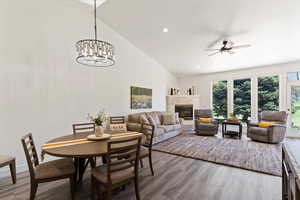 Dining room with light wood finished floors, a high end fireplace, recessed lighting, ceiling fan, and high vaulted ceiling