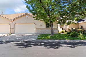 View of front of house with driveway, a garage, stucco siding, and brick siding