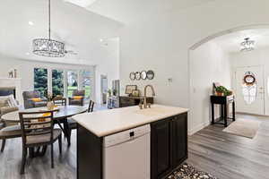 Kitchen featuring a chandelier, light countertops, lofted ceiling, dishwasher, and pendant lighting