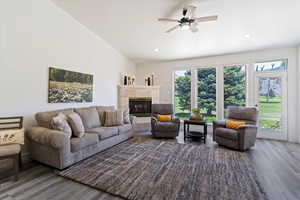 Living area featuring a tile fireplace, wood finished floors, a ceiling fan, lofted ceiling, and recessed lighting