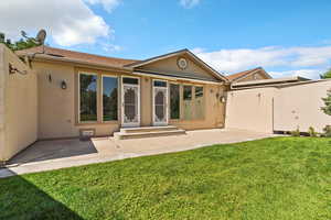 Back of property with stucco siding, a patio, and a lawn