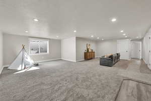 Unfurnished living room featuring light carpet, recessed lighting, and a textured ceiling