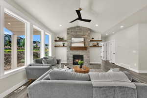 Living room with vaulted ceiling, a fireplace, wood finished floors, a ceiling fan, and recessed lighting