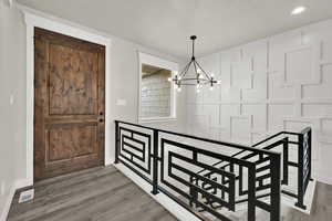 Entryway featuring a decorative wall, light wood-type flooring, a chandelier, and recessed lighting