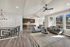 Living room featuring a chandelier, vaulted ceiling, light wood finished floors, a ceiling fan, and recessed lighting