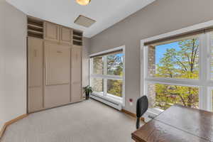 Home office with baseboard heating, light colored carpet, and a baseboard radiator