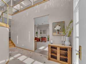 Bar featuring a fireplace, healthy amount of natural light, light tile patterned floors, light carpet, and a towering ceiling