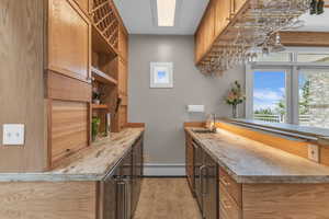 Bar area with light countertops, a baseboard heating unit, open shelves, and brown cabinetry