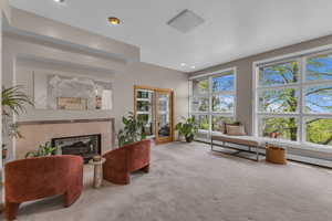 Carpeted living room with a tiled fireplace, a baseboard heating unit, and recessed lighting