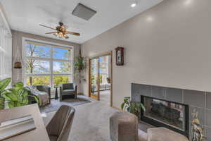 Living area featuring a tile fireplace, a ceiling fan, and carpet