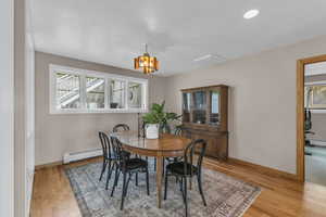 Dining room with light wood-style flooring, a chandelier, a baseboard heating unit, and recessed lighting