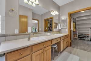 Bathroom with a spacious closet, double vanity, and light tile patterned flooring