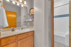 Bathroom with vanity, light tile patterned floors, and washtub / shower combination
