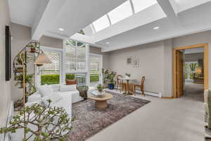 Living area featuring carpet, beamed ceiling, baseboard heating, a skylight, and recessed lighting