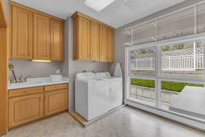 Washroom with a baseboard radiator, light floors, cabinet space, and washer and clothes dryer