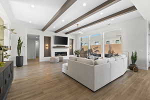Living room with beam ceiling, light wood-type flooring, recessed lighting, and a glass covered fireplace